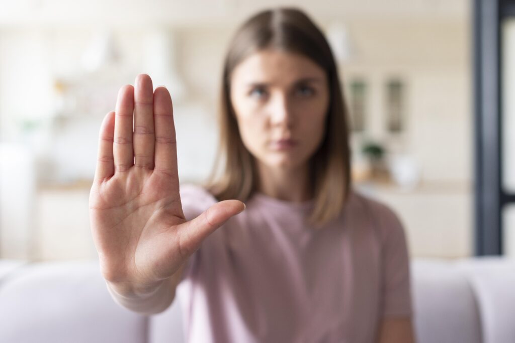 Mulher fazendo sinal de pare, representando a denúncia contra o assédio moral.