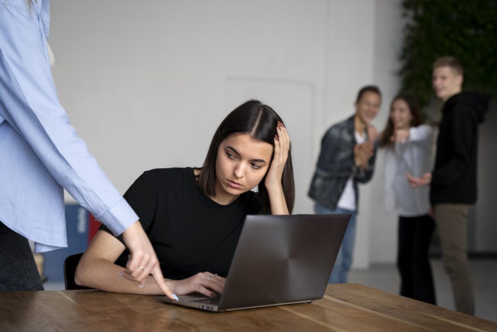 Mulher sofrendo assédio no trabalho enquanto colegas zombam ao fundo.